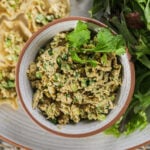 A bowl of mashed fish with chopped greens topped with a few cilantro leaves.