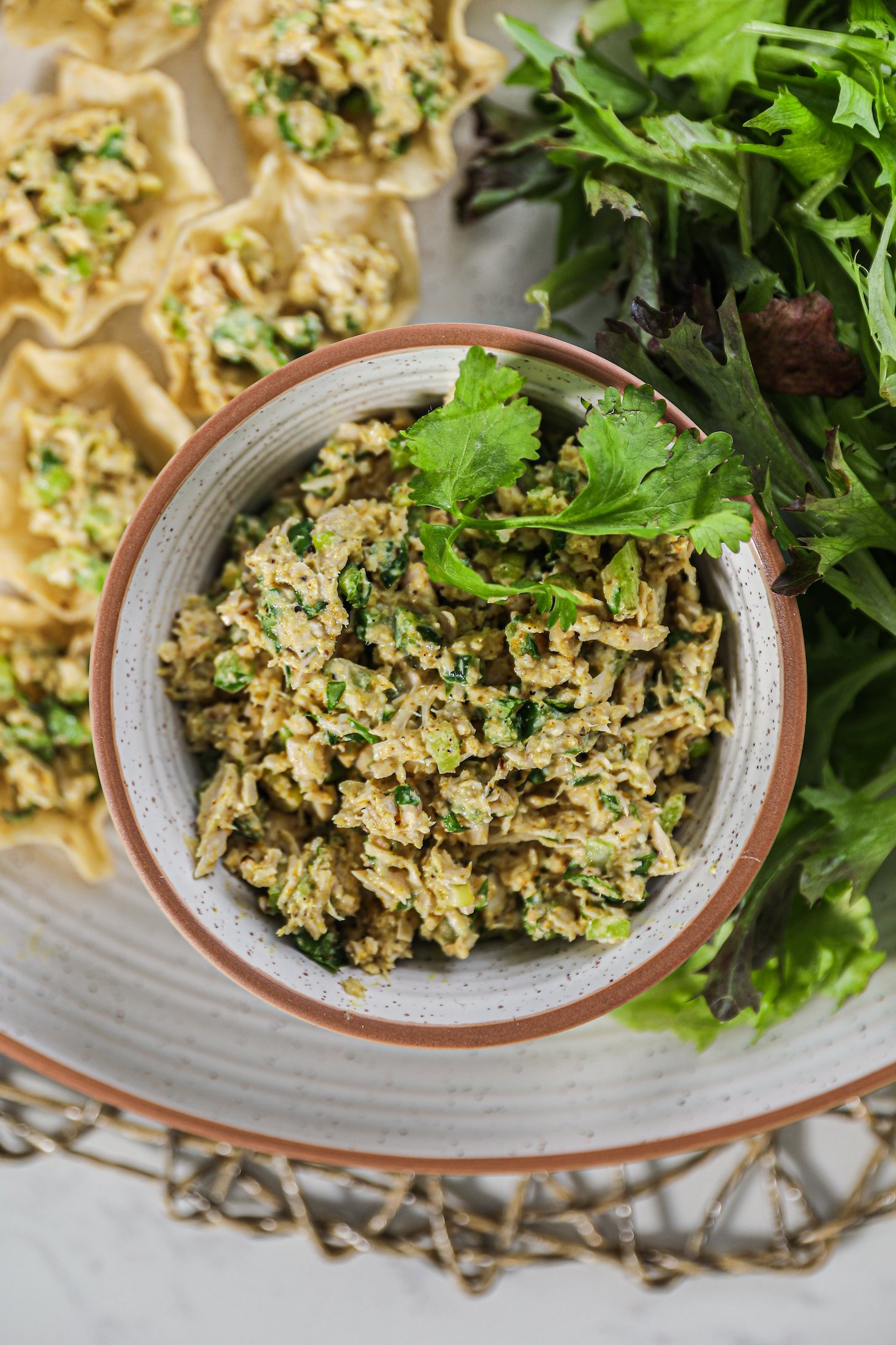 A bowl of mashed fish with chopped greens topped with a few cilantro leaves.