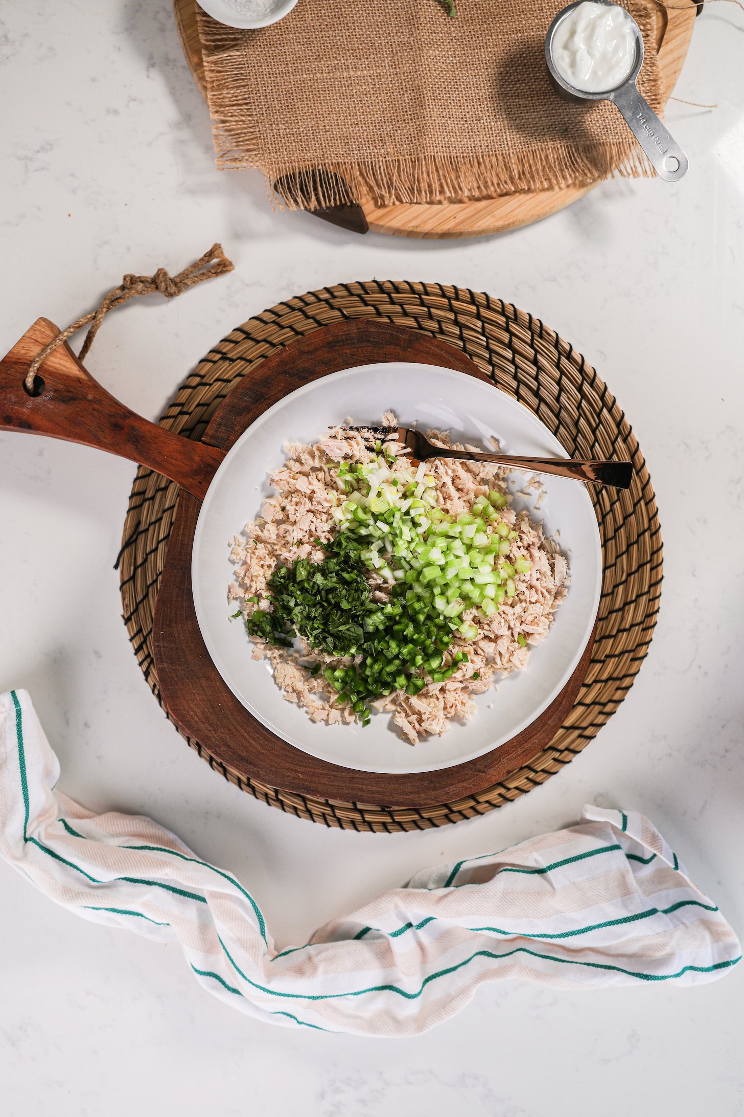 A bowl of minced fish topped with green vegetables and chopped herbs.