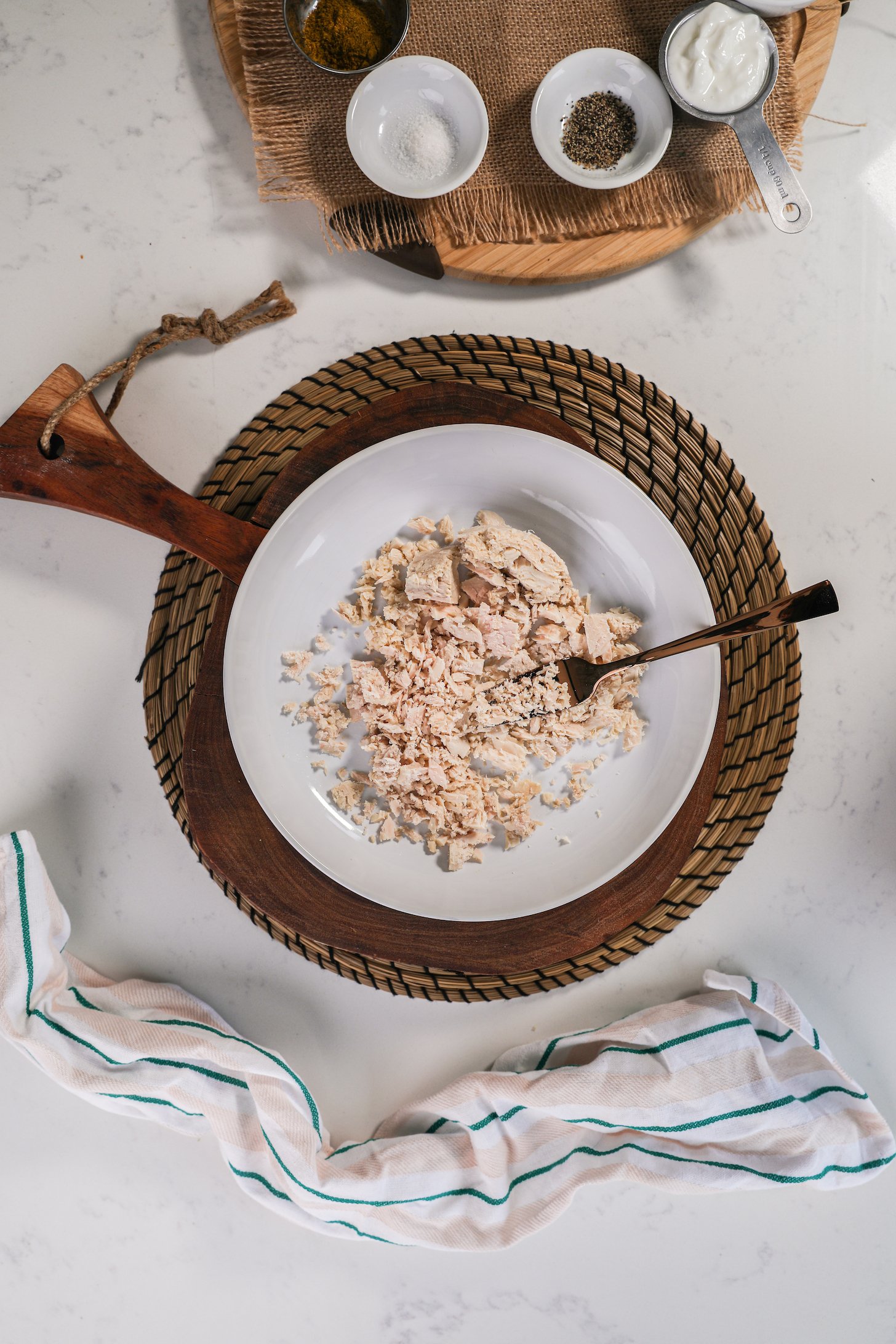 A bowl of mashed fish with a fork displayed on a wooden board.