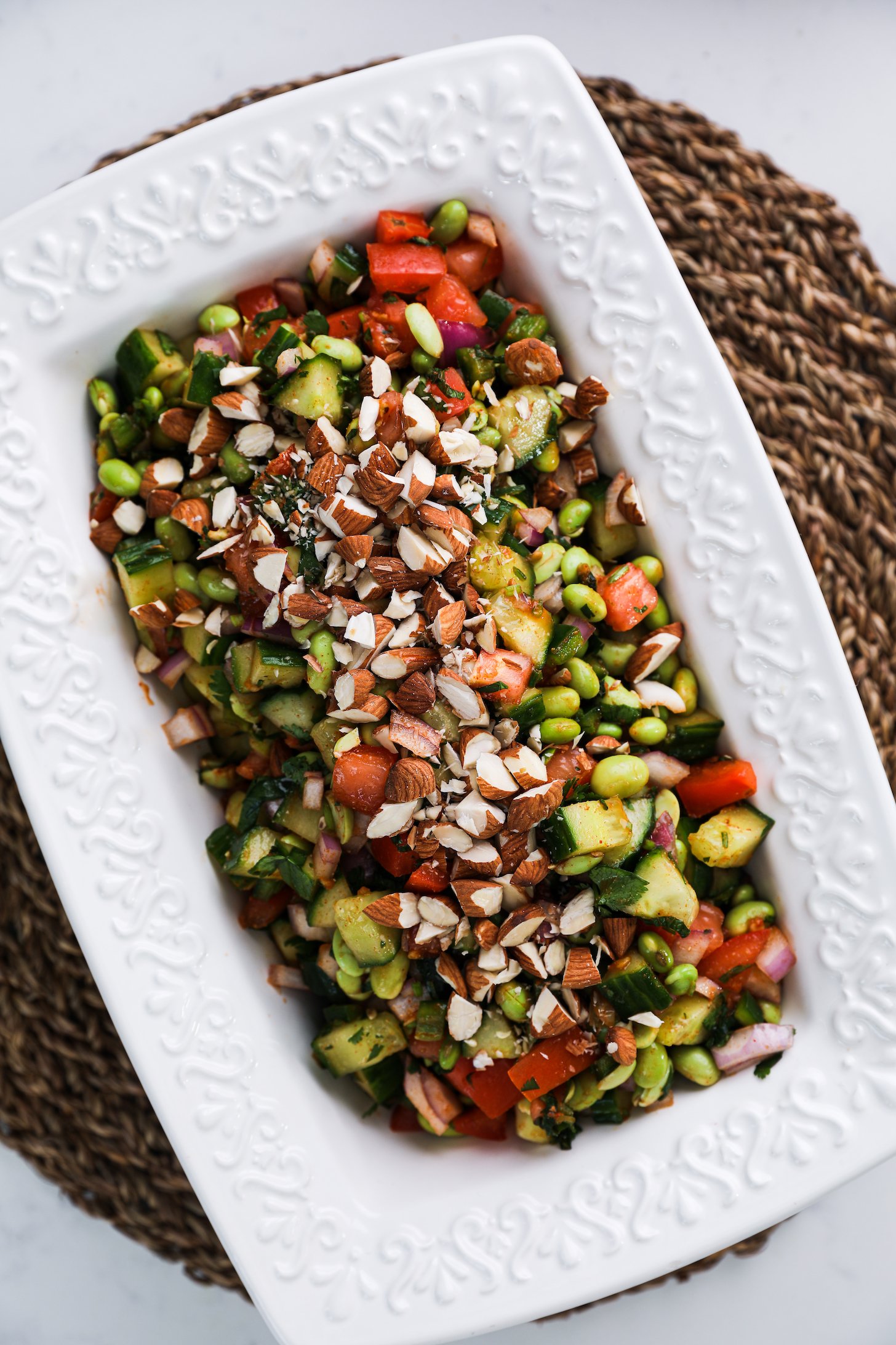 Top view of a white bowl filled with chopped vegetables, beans and topped with almonds.