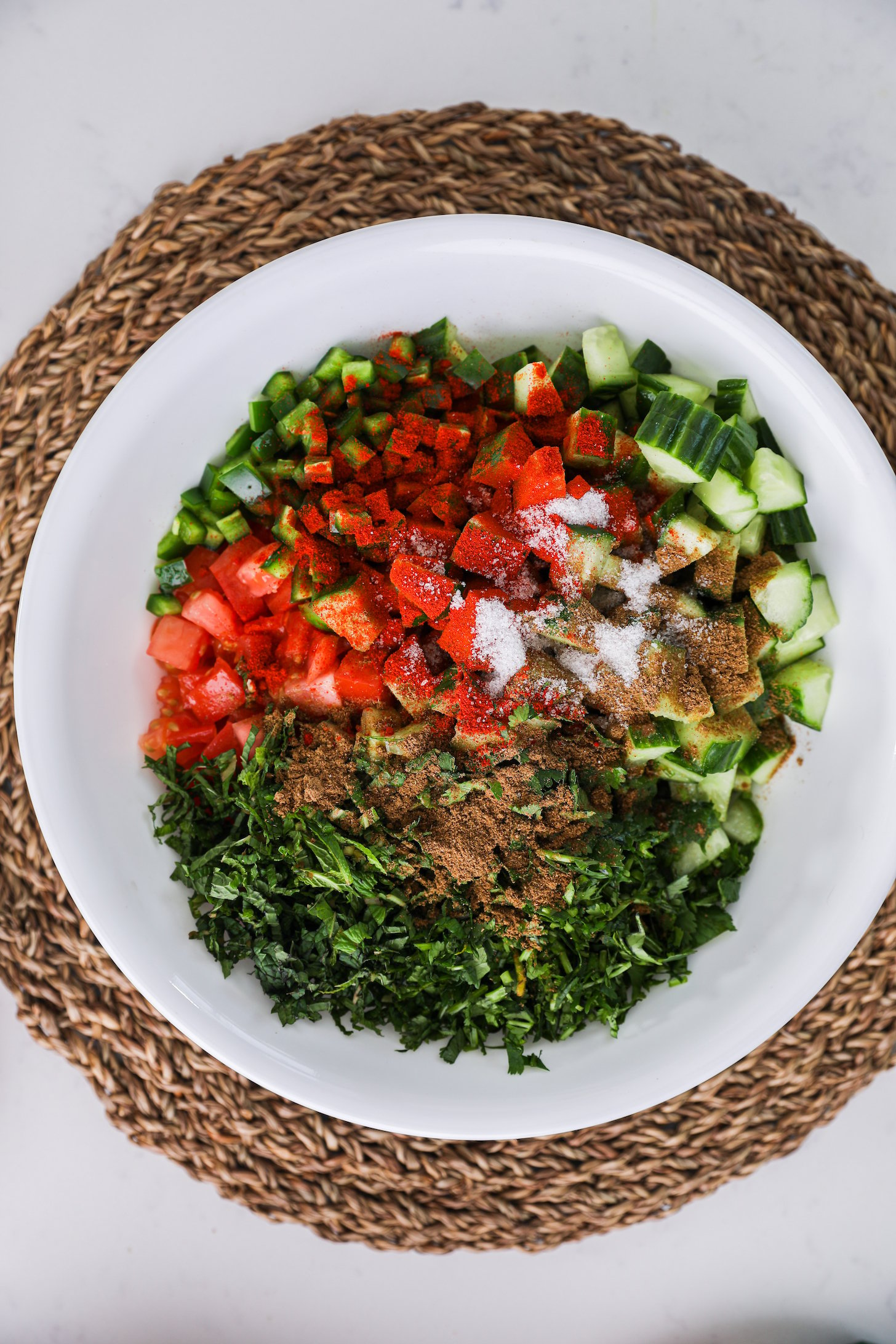 Top view of chopped vegetables and herbs sprinkled with powdered spices.