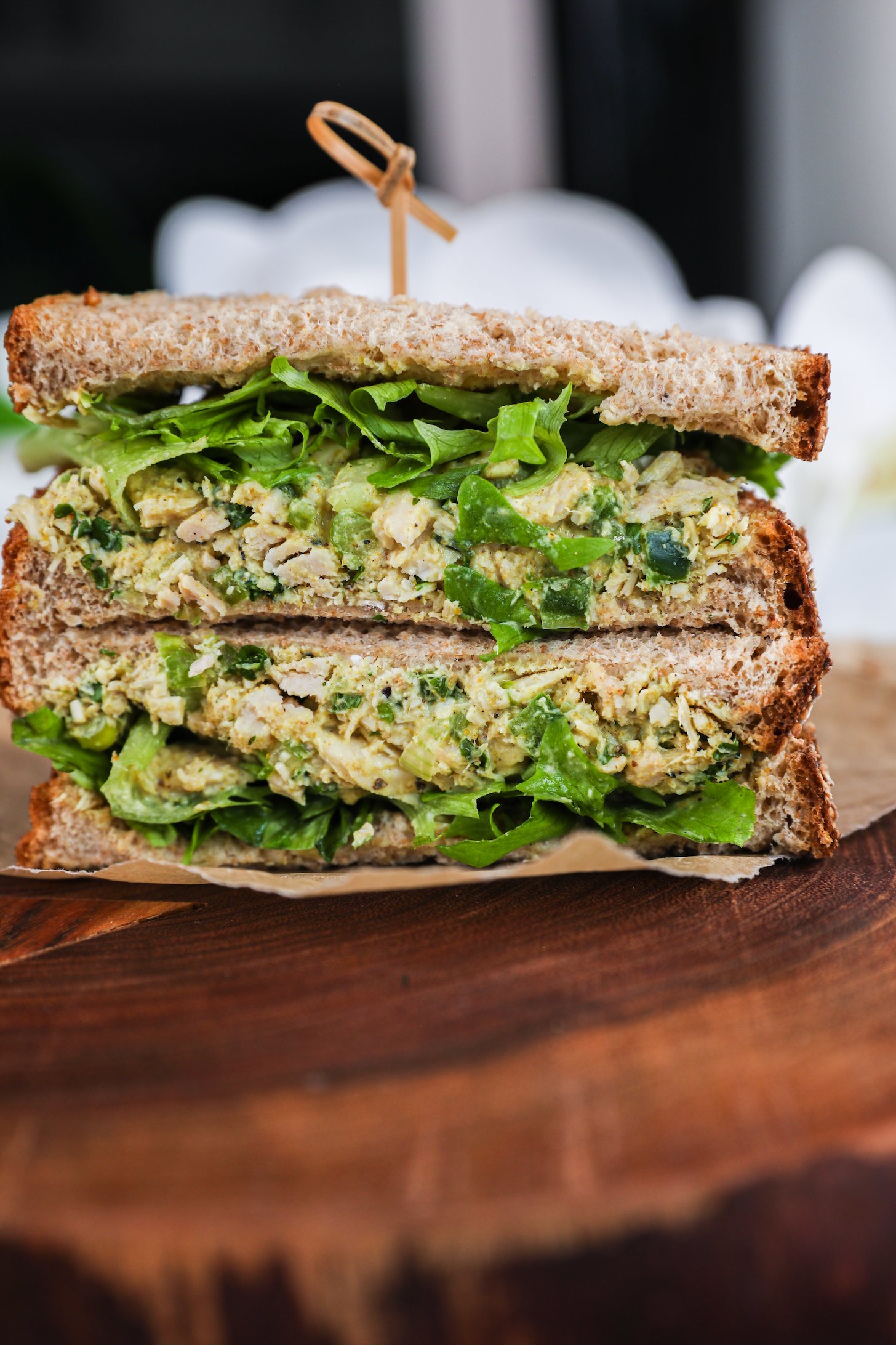 Close up shot of a stack of two sandwiches filled with greens and white tuna.