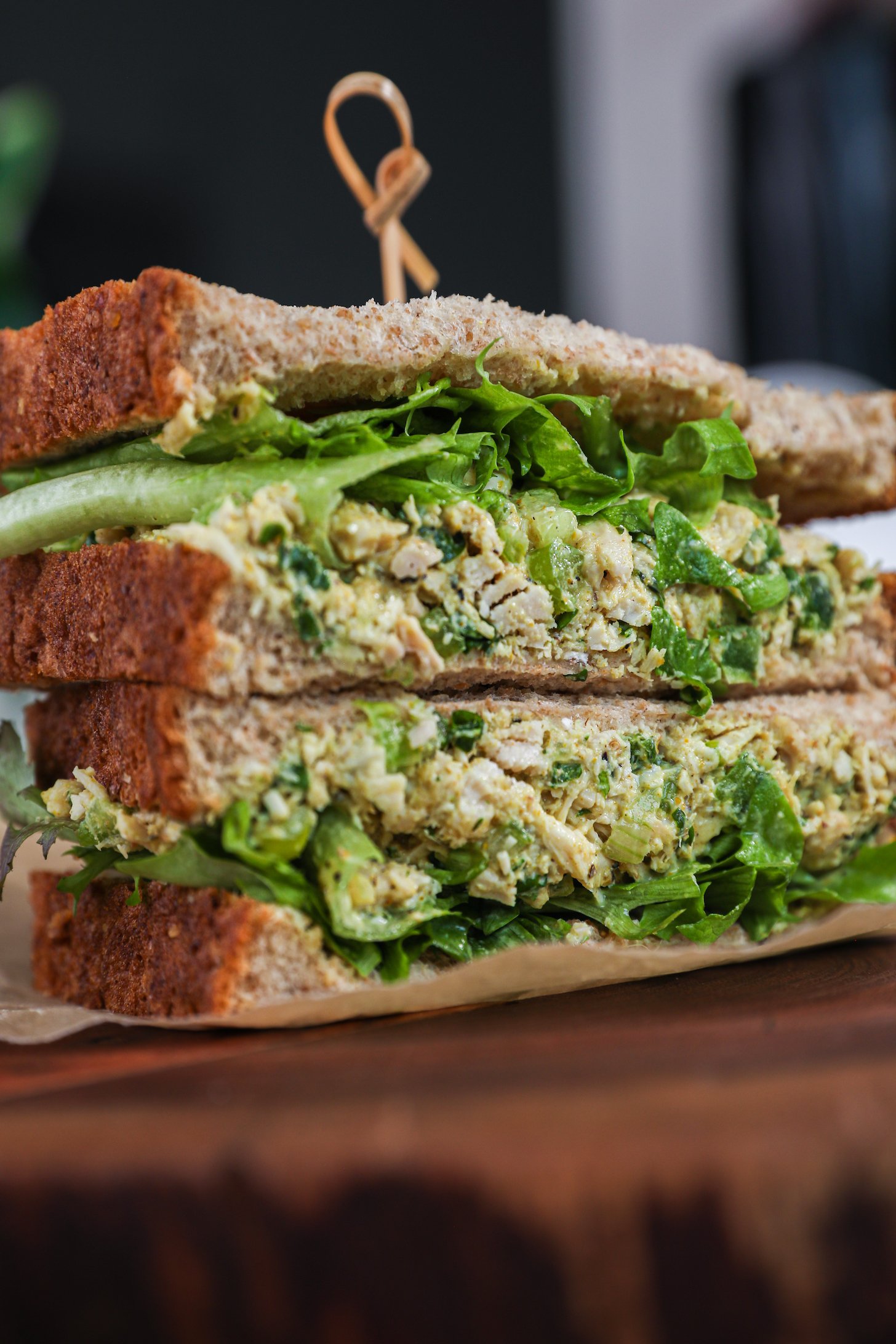 A close up angled shot of a stack of two sandwiches filled with greens and white tuna fish.