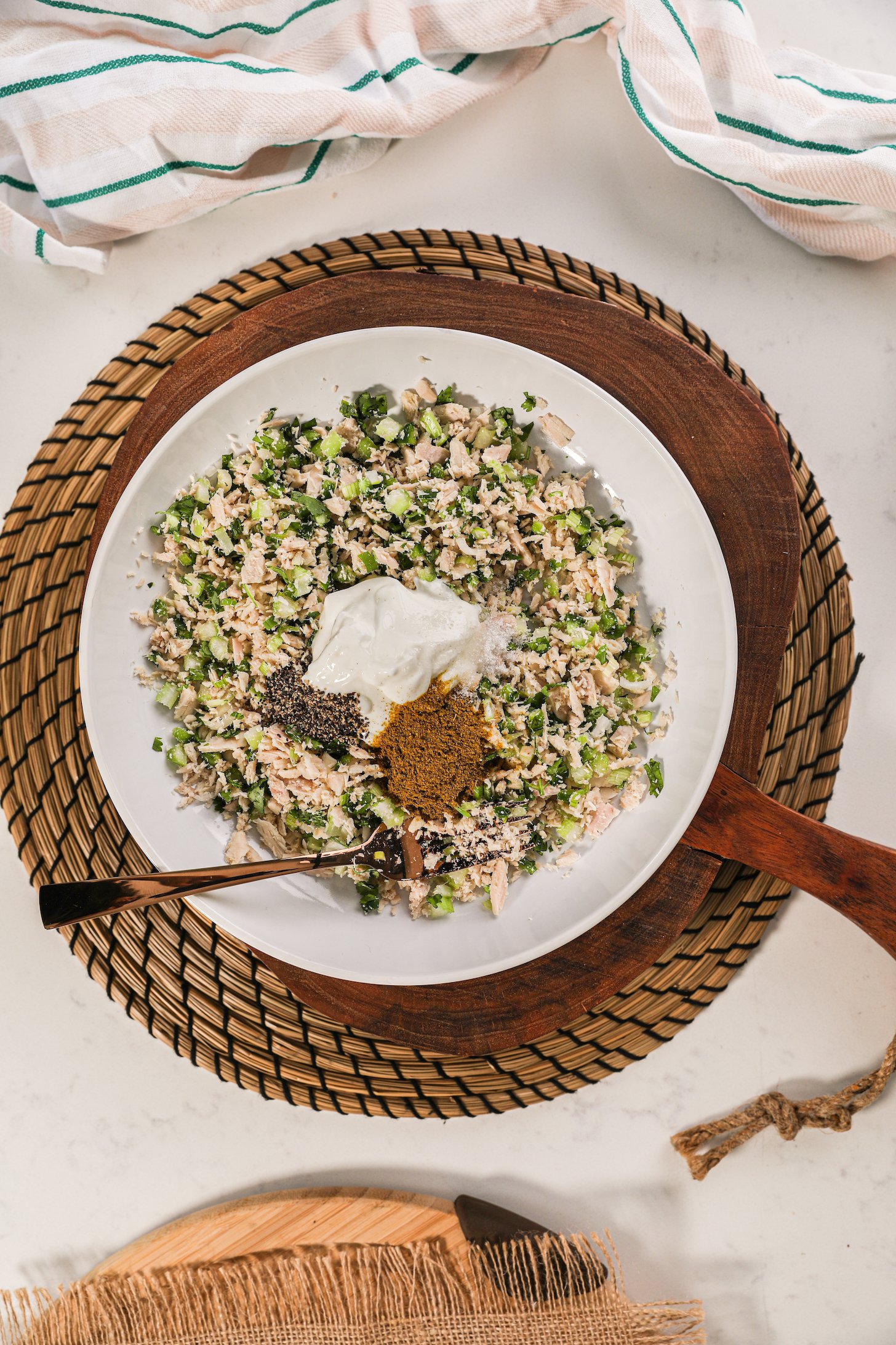 A bowl of mashed fish and vegetables topped with a dollop of yogurt and spices.