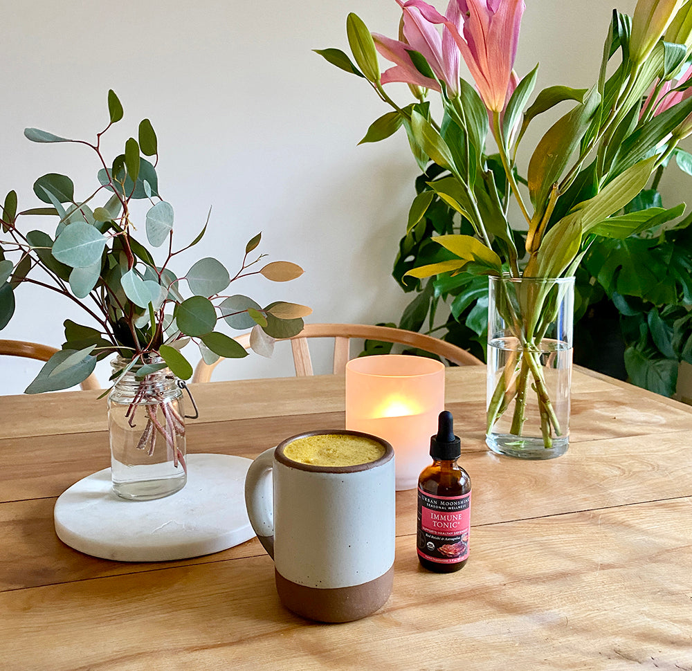 DIY golden milk with immune tonic and candle on table with flowers