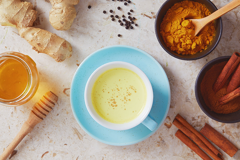 Golden milk ingredients: honey, ginger, cinnamon, turmeric, black peppercorns