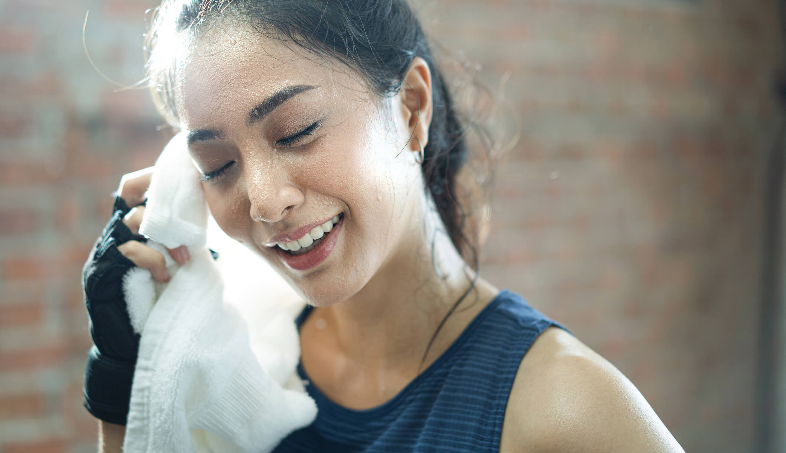 Woman wiping sweat off of her face with a towel