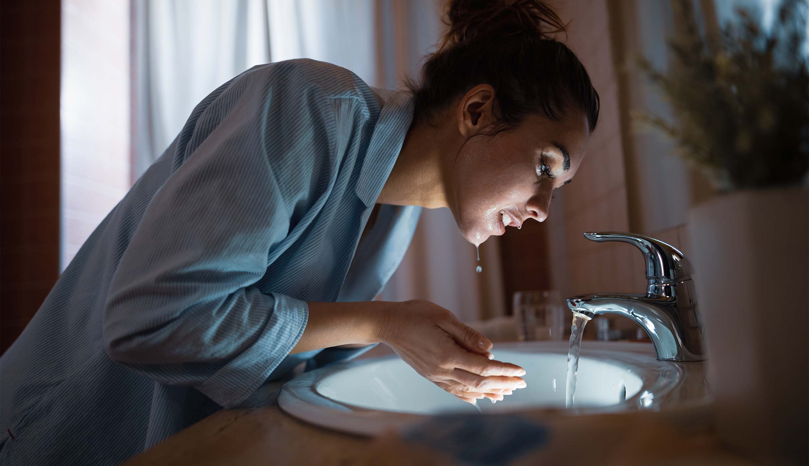 Woman washing her face at the bathroom sink before bedtime