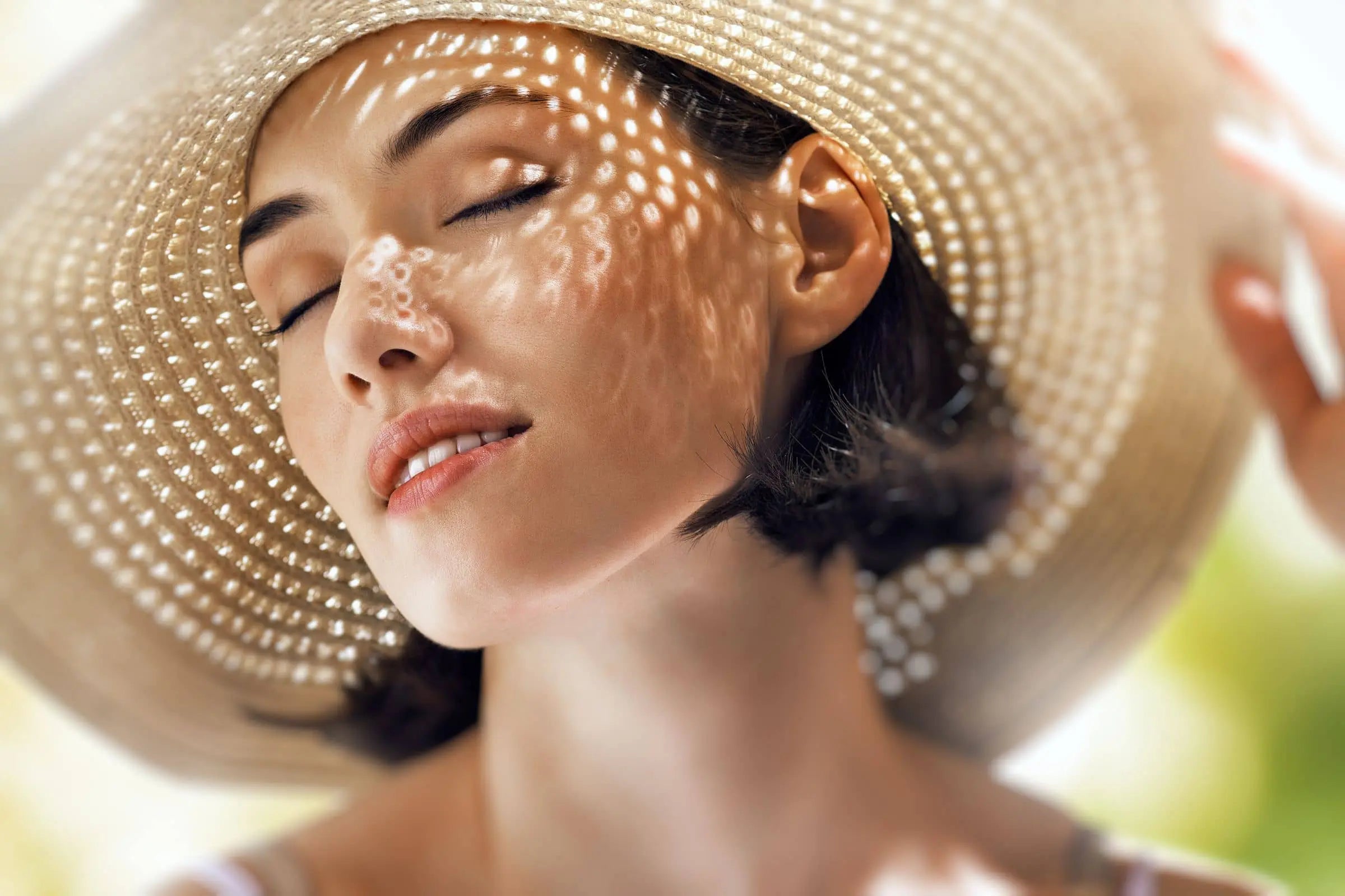 Woman in a hat protecting her face from the summer sin