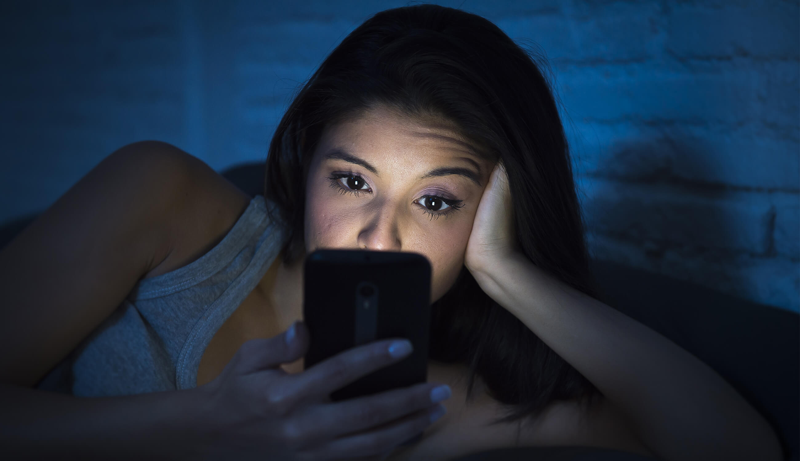 Woman looking at phone in bed